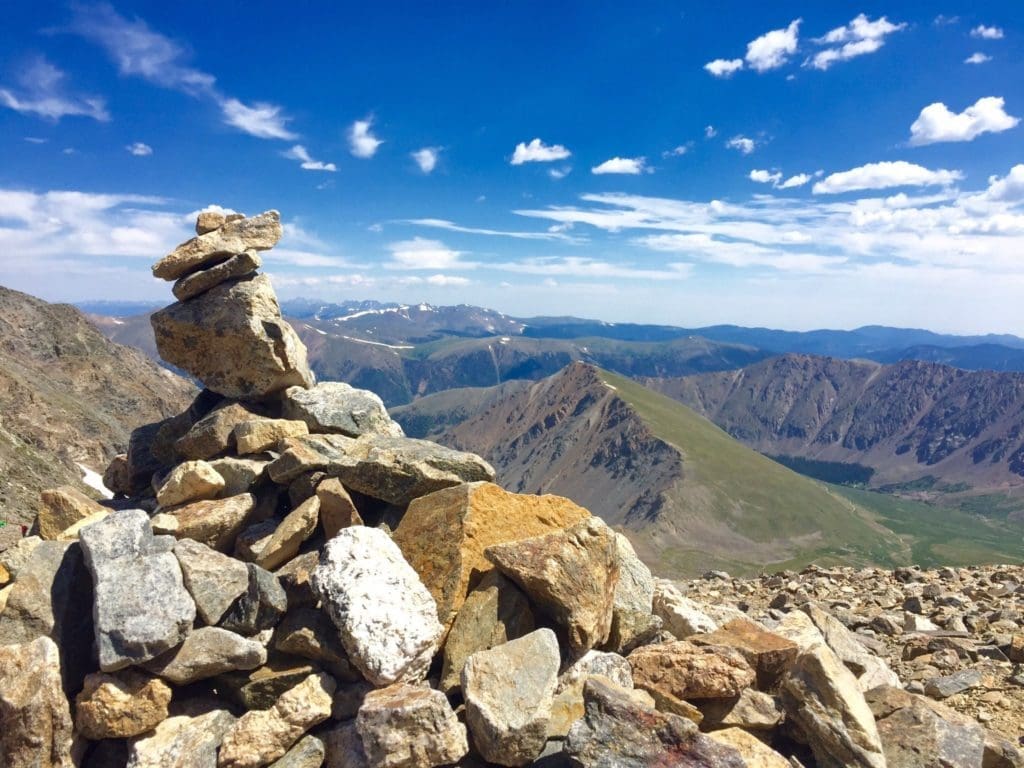 Image of rock pile from top of mountain, lots of mountains in background